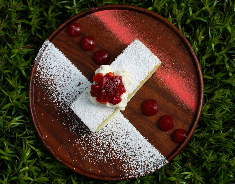 Aubergine dessert on a red plate surrounded by greenery