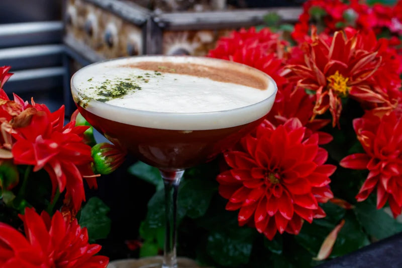 A cocktail framed by red flowers