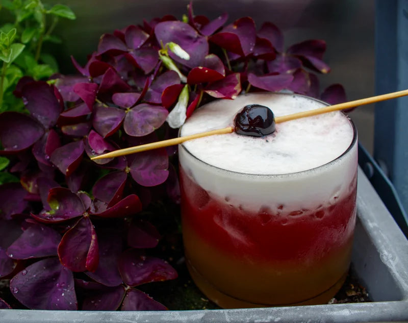 A cocktail with purple flowers