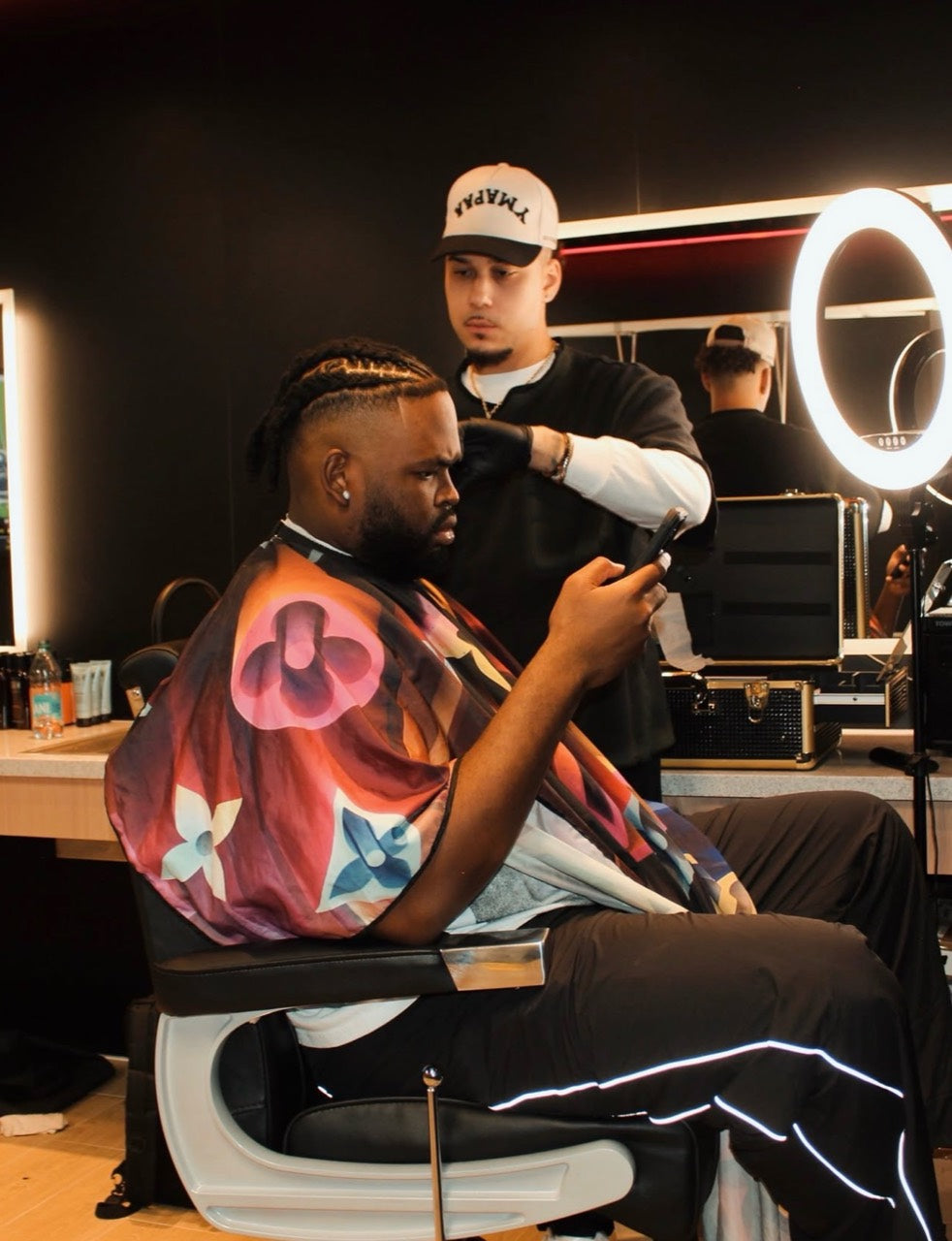 Anthony Sessa working on a client’s haircut with his open barber case beside him